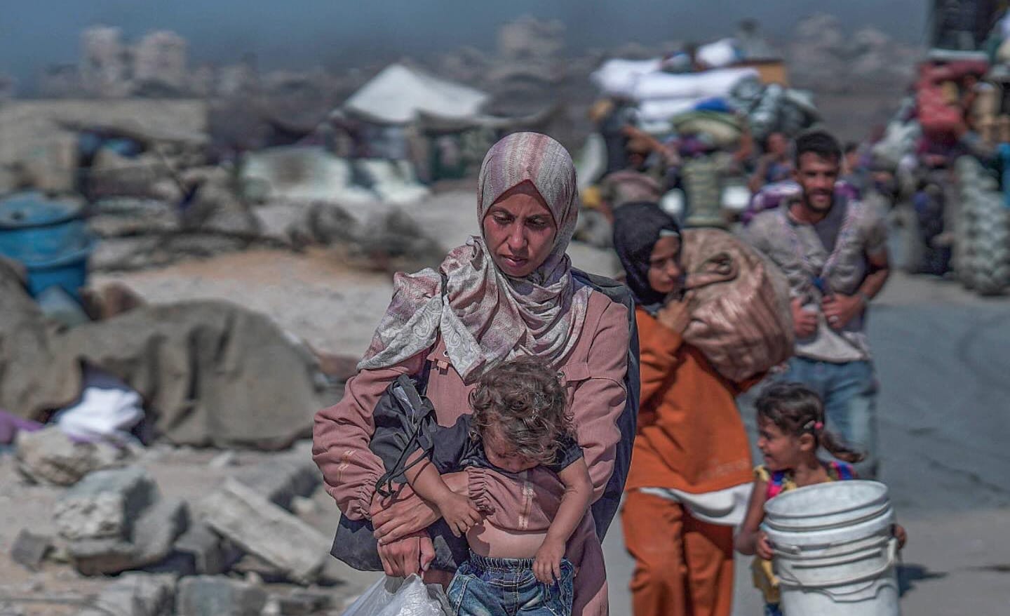 Una mujer gazatí camina con su bebé en brazos. Foto: @Timesofgaza (X)