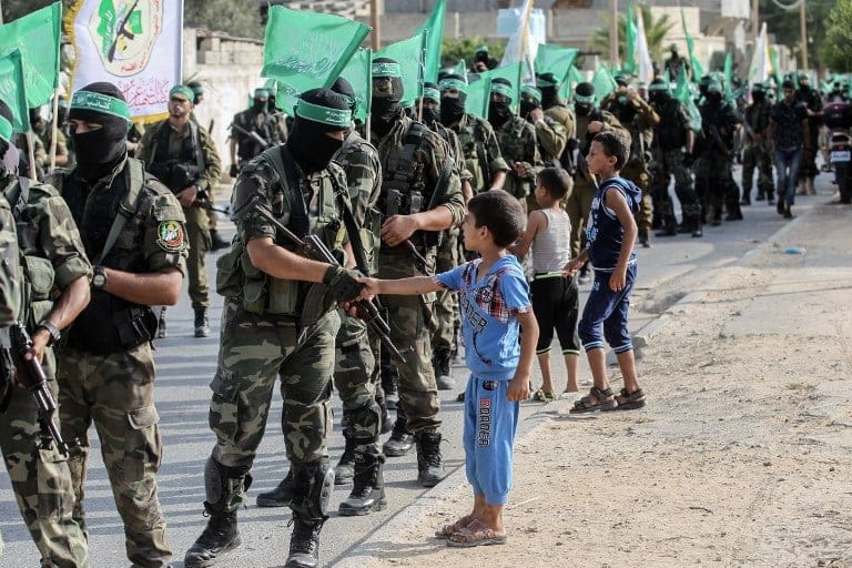 Un niño estrecha su mano a un combatiente de las Brigadas Al Qassam de Hamas en Khan Yunis (Franja de Gaza, Palestina), 20 de julio de 2017. Foto: AFP PHOTO / SAID KHATIB.