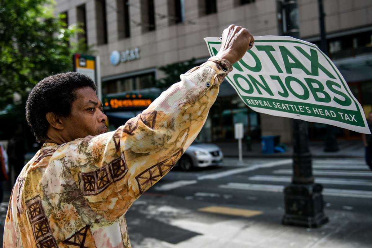 Imagen de archivo de un manifestante en Seattle sosteniendo un cartel contra los impuestos sobre las rentas del trabajo. Foto: Tim Mossholder/Unsplash