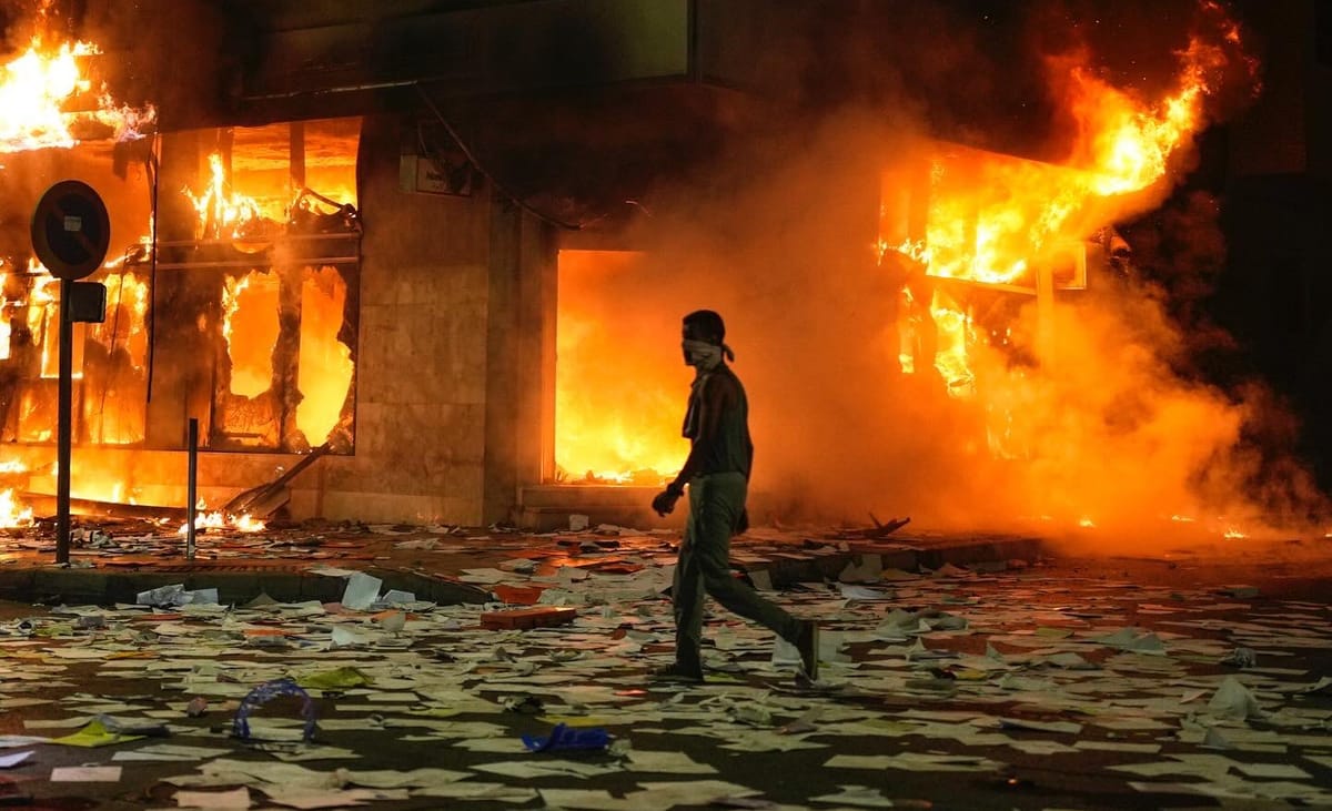 Un joven manifestante camina delante de un edificio incendiado en las protestas de Marruecos. Foto: @mosaaberizing (X)