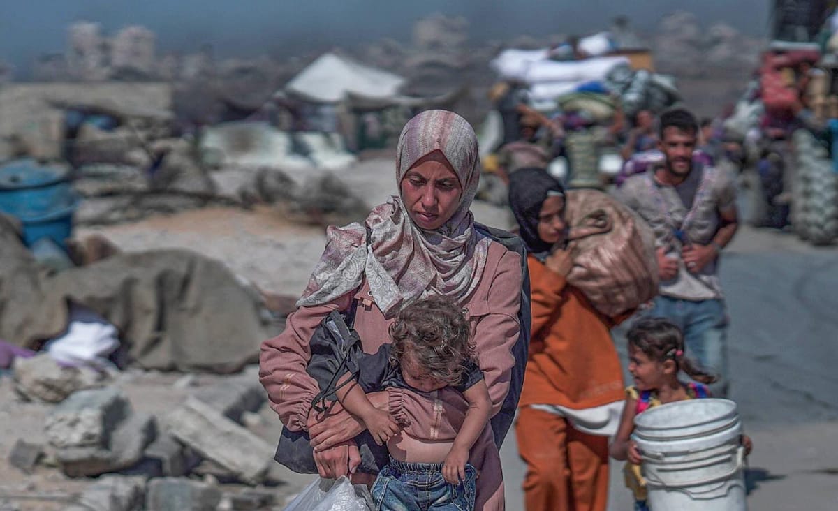 Una mujer gazatí camina con su bebé en brazos. Foto: @Timesofgaza (X)