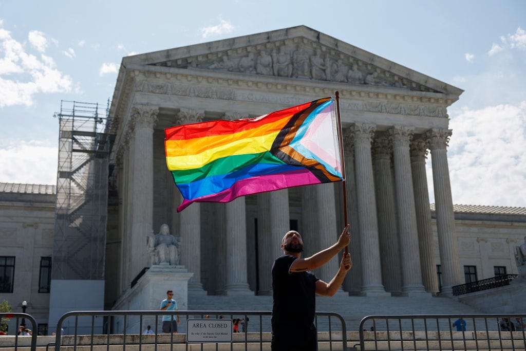 Una persona ondea la bandera arcoíris frente a la sede del Tribunal Supremo. Foto: AOL