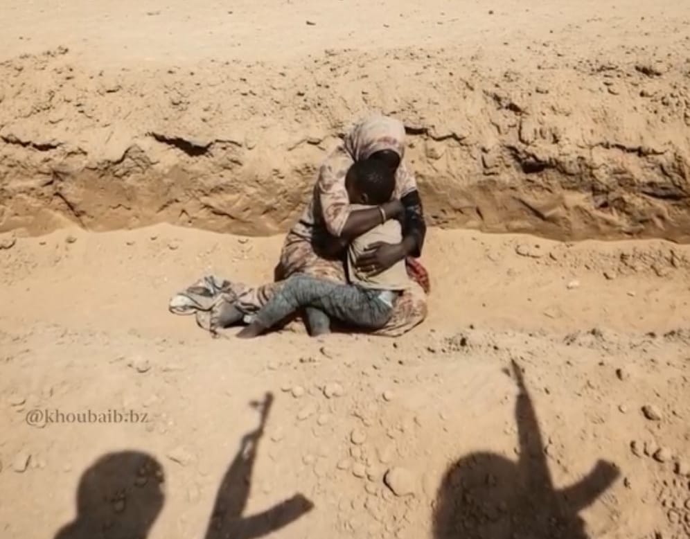 Una mujer sostiene a su niño en Sudán ante hombres armados. Foto: @khouabib.bz (X)