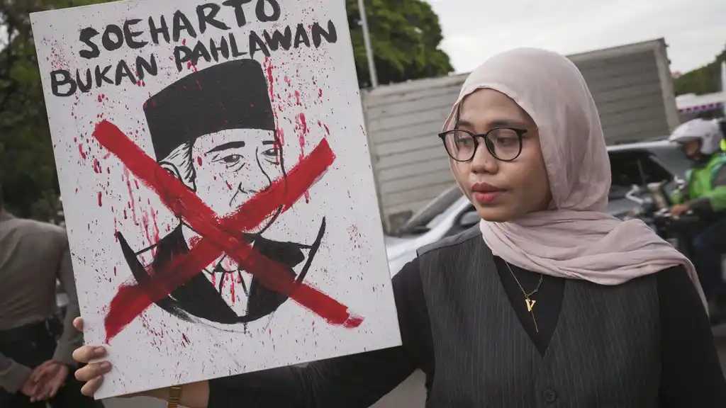 Una mujer sostiene un cartel contra Suharto en protestas indonesias. Foto: Kyodo News/Getty Images.