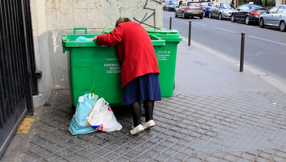 Una mujer busca comida en un contenedor de basura en París. Foto: fakirpresse.info