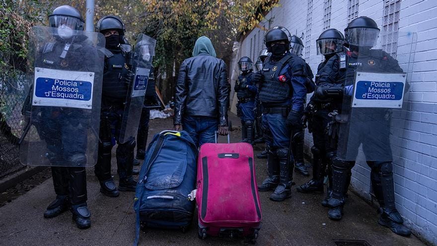 Uno de los desalojados del B9 camina entre policías. Foto: elperiódico.com