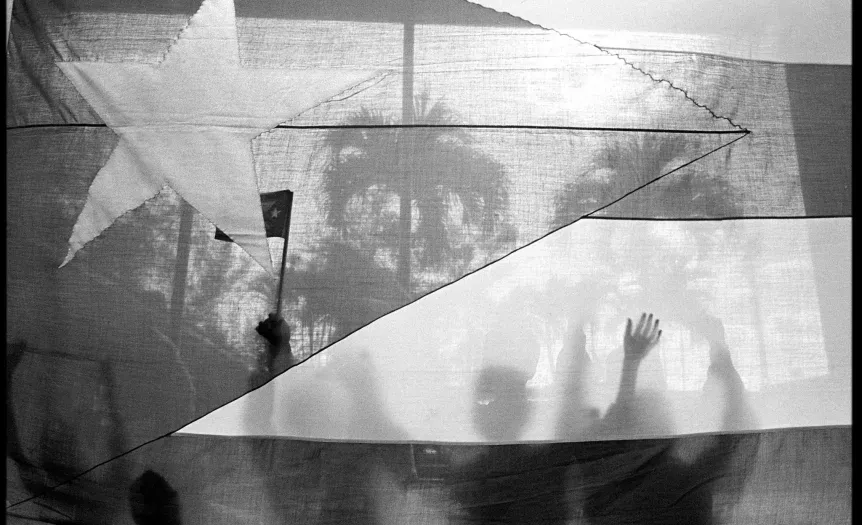 Imagen de archivo de personas tras una bandera cubana. Foto: Cristóbal Herrera/Sin título/De la serie "Cuba dura", 2000.