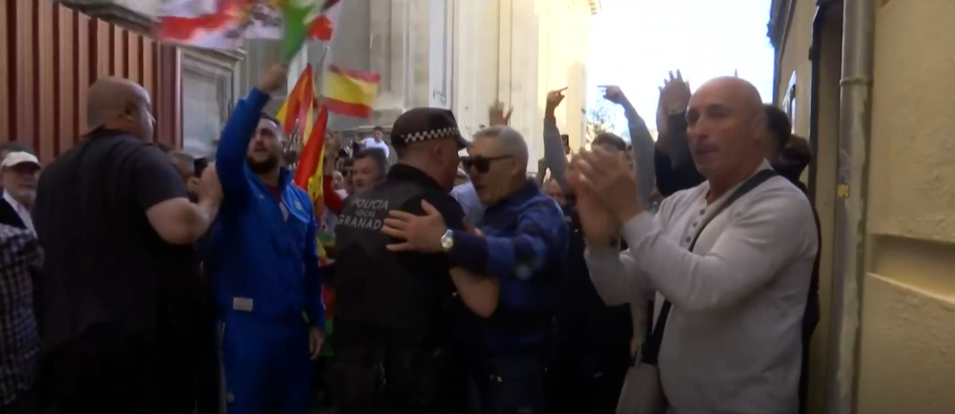 Un policía local de Granada y un asistente al mitin de Vox conversan amistosamente en los enfrentamientos con antifascistas. Foto: @telediario_tve (X)